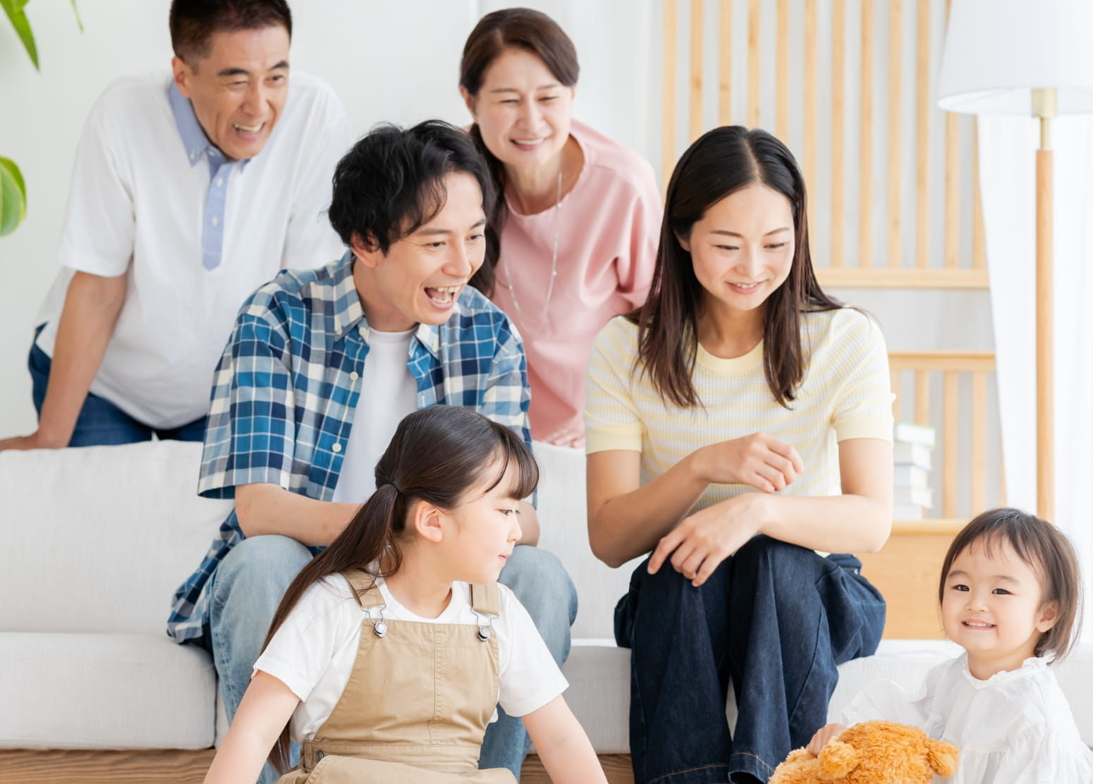 家族三世代が揃って一番小さな子を笑顔で見つめている